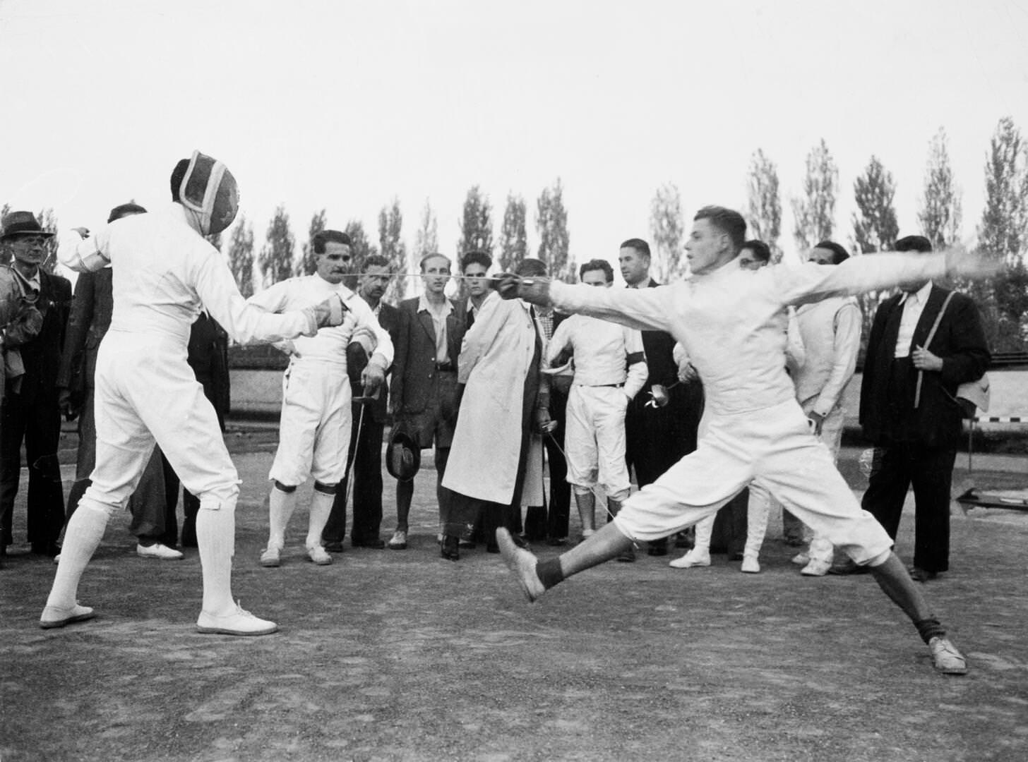 [Vívók és közönségük, közöttük (a fejvédjét tartó) Berczelly Tibor olimpiai bajnok kardvívó egy sportbemutatón, Budapest], 1948. szeptember, Robert Capa, Courtesy International Center of Photography | [Fencers and spectators including Olympic champion saber fencer Tibor Berczelly (holding helmet) at a sports demonstration, Budapest] September 1948, Robert Capa, Courtesy International Center of Photography